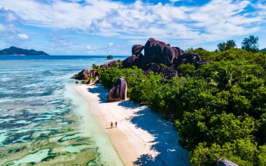 Anse Source dArgent, La Digue Seychelles, Anse Source DArgent, La Digue Seychelles 'de lüks bir tatil sırasında tropikal bir plajda yaşayan birkaç beyaz erkek ve Asyalı kadın.
