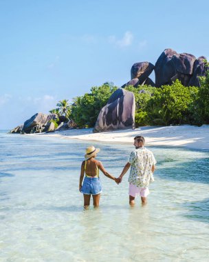 Anse Source dArgent, La Digue Seychelles, Anse Source DArgent, La Digue Seychelles 'de lüks bir tatil sırasında tropikal bir plajda yaşayan birkaç beyaz erkek ve Asyalı kadın.