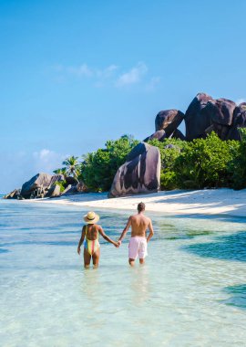 Anse Source dArgent, La Digue Seychelles, Anse Source DArgent, La Digue Seychelles 'de lüks bir tatil sırasında tropikal bir plajda yaşayan birkaç beyaz erkek ve Asyalı kadın.