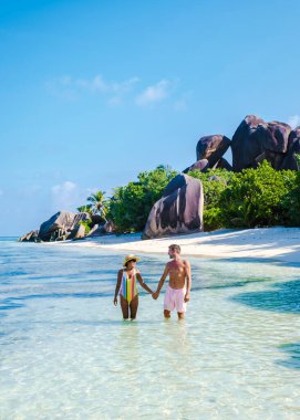 Anse Source dArgent, La Digue Seychelles, Anse Source DArgent, La Digue Seychelles 'de lüks bir tatil sırasında tropikal bir plajda yaşayan birkaç beyaz erkek ve Asyalı kadın.