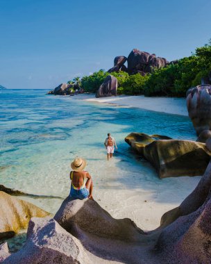 Anse Source dArgent, La Digue Seychelles, Anse Source DArgent, La Digue Seychelles 'de lüks bir tatil sırasında tropikal bir plajda yaşayan birkaç beyaz erkek ve Asyalı kadın.