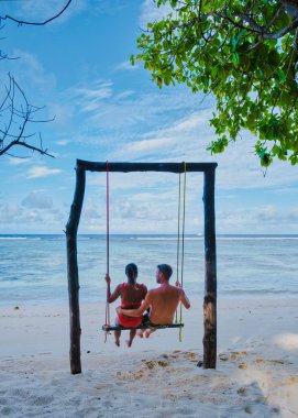 Anse Source dArgent, La Digue Seychelles, Anse Source DArgent, La Digue Seychelles 'de lüks bir tatil sırasında tropikal bir plajda yaşayan birkaç beyaz erkek ve Asyalı kadın.