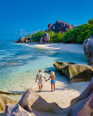 Anse Source dArgent, La Digue Seychelles, Anse Source DArgent, La Digue Seychelles 'de lüks bir tatil sırasında tropikal bir plajda yaşayan birkaç beyaz erkek ve Asyalı kadın.