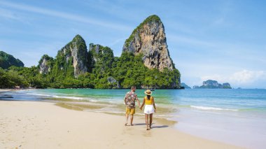 Railay Beach Krabi Tayland, Railay Krabi 'nin tropikal plajı, kumsalda bir çift kadın ve erkek, Tayland' da geleneksel uzun bir teknesi olan huzurlu Railay Kumsalı manzarası..