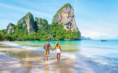 Railay Beach Krabi Tayland, Railay Krabi 'nin tropikal plajı, kumsalda bir çift kadın ve erkek, Tayland' da geleneksel uzun bir teknesi olan huzurlu Railay Kumsalı manzarası..