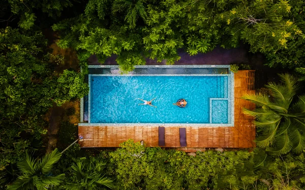 泰国克拉比丛林里的一个游泳池里 一对男女正在游泳 在泰国丛林里 一架无人驾驶飞机从游泳池上方俯瞰着天空 — 图库照片