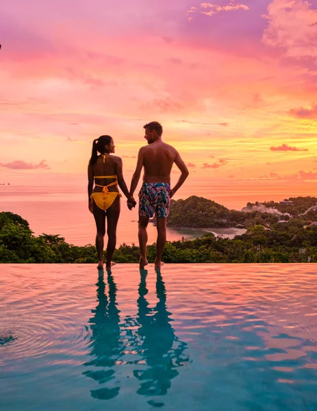 一对年轻夫妇在热带岛屿度假时在游泳池边游泳 日落时 男人和女人在无穷无尽的池子里 在泰国的豪华游泳池别墅游泳池度假 — 图库照片