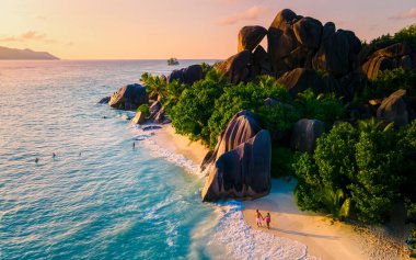 Anse Source dArgent, La Digue Seychelles, Seyşeller 'de lüks bir tatil sırasında tropikal bir plajda yaşayan genç bir çift. Tropik sahil Anse Kaynak dArgent, La Digue Seyşeller