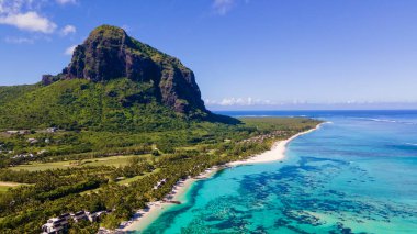 Le Morne plajı Mauritius Tropikal plajı. Palmiye ağaçları, beyaz kum mavisi okyanus ve şemsiyeli plaj yatakları, güneş sandalyeleri ve tropik bir sahildeki palmiye ağacının altında şemsiyeler. Mauritius Le Morne