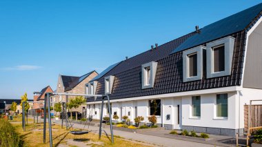 Newly build houses with solar panels attached on the roof against a sunny sky Close up of a new building with black solar panels. Zonnepanelen, Zonne energie, Translation: Solar panel, , Sun Energy. 