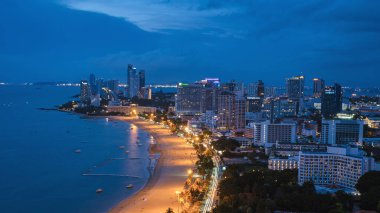 Pattaya Thailand May 2022, beach road during sunset at a tropical beach with palm trees. Pattaya Thailand skyline of the city. 