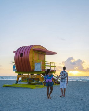 Miami Beach, a couple on the beach at Miami Florida, lifeguard hut Miami Asian women and caucasian men on the beach during sunset
