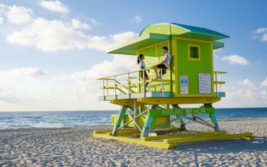 Miami Beach, a couple on the beach at Miami Florida, lifeguard hut Miami Asian women and caucasian men on the beach during sunset. man and woman watching sunrise