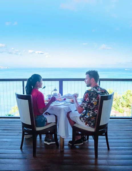 couple men and women having breakfast with a look over the ocean of Saint Lucia Caribbean. men and women on a luxury vacation in St Lucia