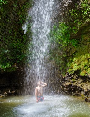 Young men relaxing at Toraille waterfall St Lucia. Saint Lucia jungle waterfall and men swimming. Toraille Falls Sain Lucia