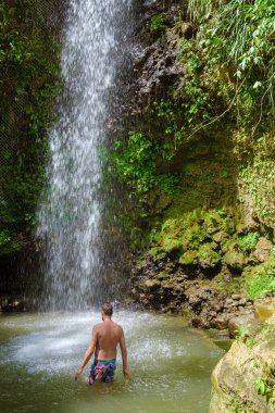 Young men relaxing at Toraille waterfall St Lucia. Saint Lucia jungle waterfall and men swimming. Toraille Falls Sain Lucia