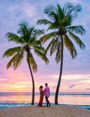 couple on the beach with palm trees watching the sunset at the tropical beach of Saint Lucia or St Lucia Caribbean. men and women on vacation in St Lucia a tropical island with palm trees