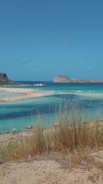 Crete Greece, Balos lagoon on Crete island, Greece. Tourists relax and bathe in the crystal clear water of Balos beach. Greece, men watching the clear ocean of Crete sitting in the sand
