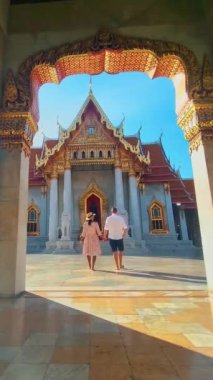 Wat Benchamabophit the marble temple, is a royal temple in the capital city of Bangkok, Thailand. couple Asian women with hat and European men visiting a temple in Bangkok