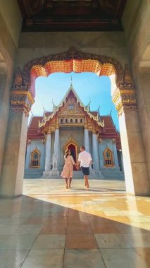 Wat Benchamabophit mermer tapınak, Tayland 'ın başkenti Bangkok' ta bulunan bir kraliyet tapınağıdır. Şapkalı birkaç Asyalı kadın ve Bangkok 'taki bir tapınağı ziyaret eden Avrupalı erkekler.