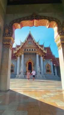 Wat Benchamabophit the marble temple, a royal temple in the capital city of Bangkok, Thailand. couple Asian women with a hat and European men visiting a temple in Bangkok during vacation in Thailand