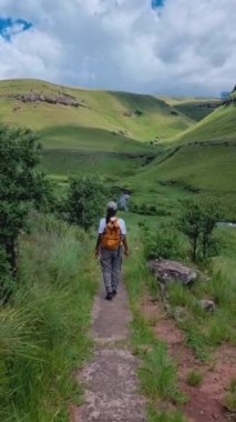 Dağlarda yürüyüş yapan genç kadın, Drakensberg Güney Afrika Kalesi, Drakensberg Dağı, Orta Drakensberg Kwazulu Natal, Güney Afrika 'da yeşil dağlar, yürüyüş yapan genç Asyalı kadın.