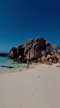 men and women on the beach of Anse Cocos La Digue Seychelles, a tropical beach during luxury vacation, Asian women and caucasian men on the beach with swimming clothes