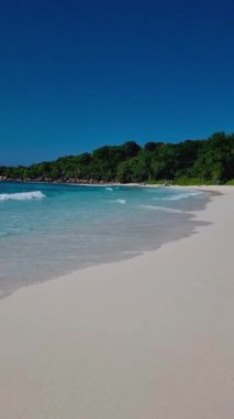 men and women on the beach of Anse Cocos La Digue Seychelles, a tropical beach during luxury vacation, Asian women and caucasian men on the beach with swimming clothes
