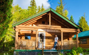 Wooden hut in an autumn forest, cabin off the grid, wooden cabin circled by colorful yellow and red fall trees. cabin in the woods British Colombia Canada Autumn. Asian women vacation Canada BC