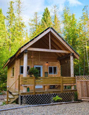 Wooden hut in an autumn forest, cabin off the grid, wooden cabin circled by colorful yellow and red fall trees. cabin in the woods British Colombia Canada Autumn. 