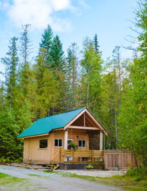 Wooden hut in an autumn forest, cabin off the grid, wooden cabin circled by colorful yellow and red fall trees. cabin in the woods British Colombia Canada Autumn. 