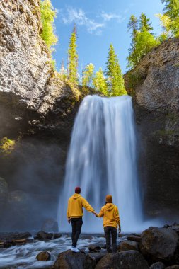 Moul Falls Canada is a Beautiful waterfall in Canada, couple of visits to Moul Falls, the most famous waterfall in Wells Gray Provincial Park. a couple of men and women standing by a waterfall