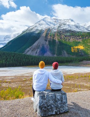 Icefields Parkway with autumn trees and snowy foggy mountains in Jasper Canada Alberta. couple of men and women on a road trip at Icefield parkway