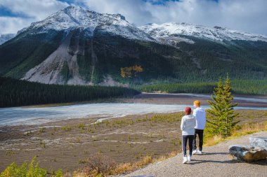 Icefields Parkway with autumn trees and snowy foggy mountains in Jasper Canada Alberta. couple of men and women on a road trip at Icefield parkway