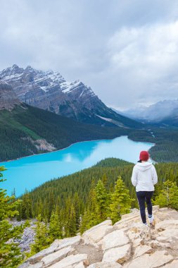 Lake Peyto in Banff National Park, Canada. Mountain Lake as a fox head is popular among tourists in Canada driving the icefields parkway. young women on top of a mountain looking out over a lake