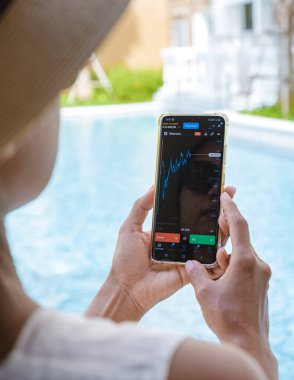 Asian woman with hat check crypto currency on their phone when on holiday 