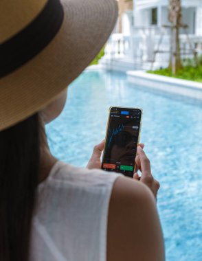 Asian woman with hat check crypto currency on their phone when on holiday 
