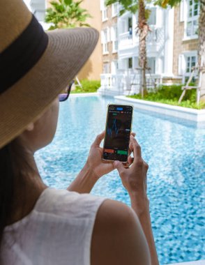 Asian woman with hat check crypto currency on their phone when on holiday 