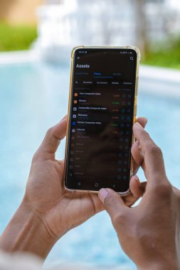 women hand with a phone checking commodity prices on her cellphone 