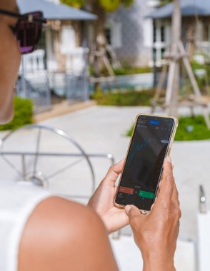 Asian woman checking cryptocurrency on their phone when on holiday , close up of hand and phone with crypto Ethereum currency