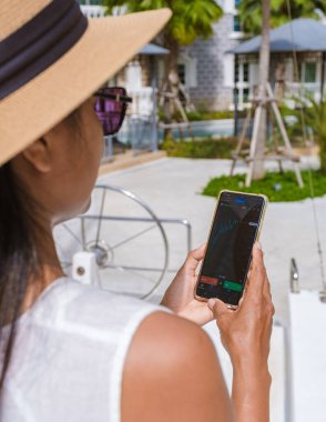 Asian women with hat check cryptocurrency on their phone when on holiday , women checking her phone on vacation 