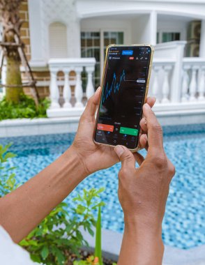 Asian women with hat check Ethereum crypto currency on their phones when on holiday. Asian women trading bitcoin on her phone