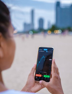 Asian women with checking Eur Usd currency on their phones when on holiday, women check Euro and USD their phone on vacation 