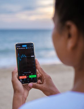 Asian women check Ethereum cryptocurrency on their phone when on holiday , women checking her phone on vacation 