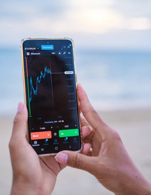 Asian women check Ethereum cryptocurrency on their phone when on holiday , women checking her phone on vacation 