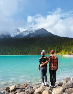 Lake Louise Banff national park, is a lake in the Canadian Rocky Mountains. A young couple of men and women standing by the lake during a cold day in Autumn in Canada