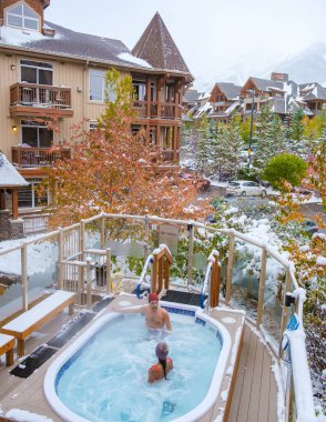 couple in the hot tub during snow in the Canadian Rockies in Canada, men, and woman in a hot tub during a luxury vacation