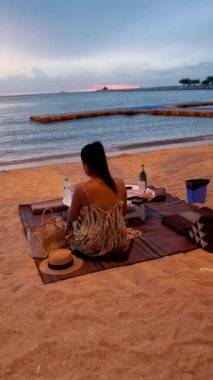women bbq cooking noodle soup during sunset in Thailand Ban Amphur beach. relaxing with bbq Thai traditional on a tropical beach with palm trees and hammock during sunset