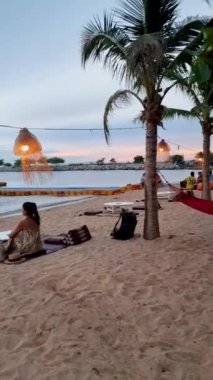 women bbq cooking noodle soup during sunset in Thailand Ban Amphur beach. relaxing with bbq Thai traditional on a tropical beach with palm trees and hammock during sunset