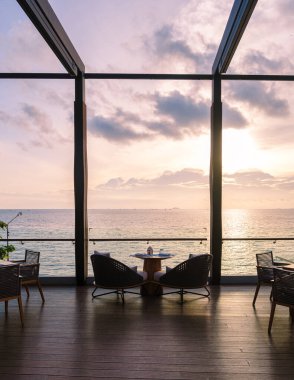 The restaurant at the oceanfront during sunset in Pattaya Thailand. Restaurant with dinner table and chairs during sunset on the beach